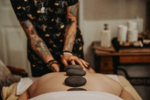 Woman with tattoos giving hot stone massage